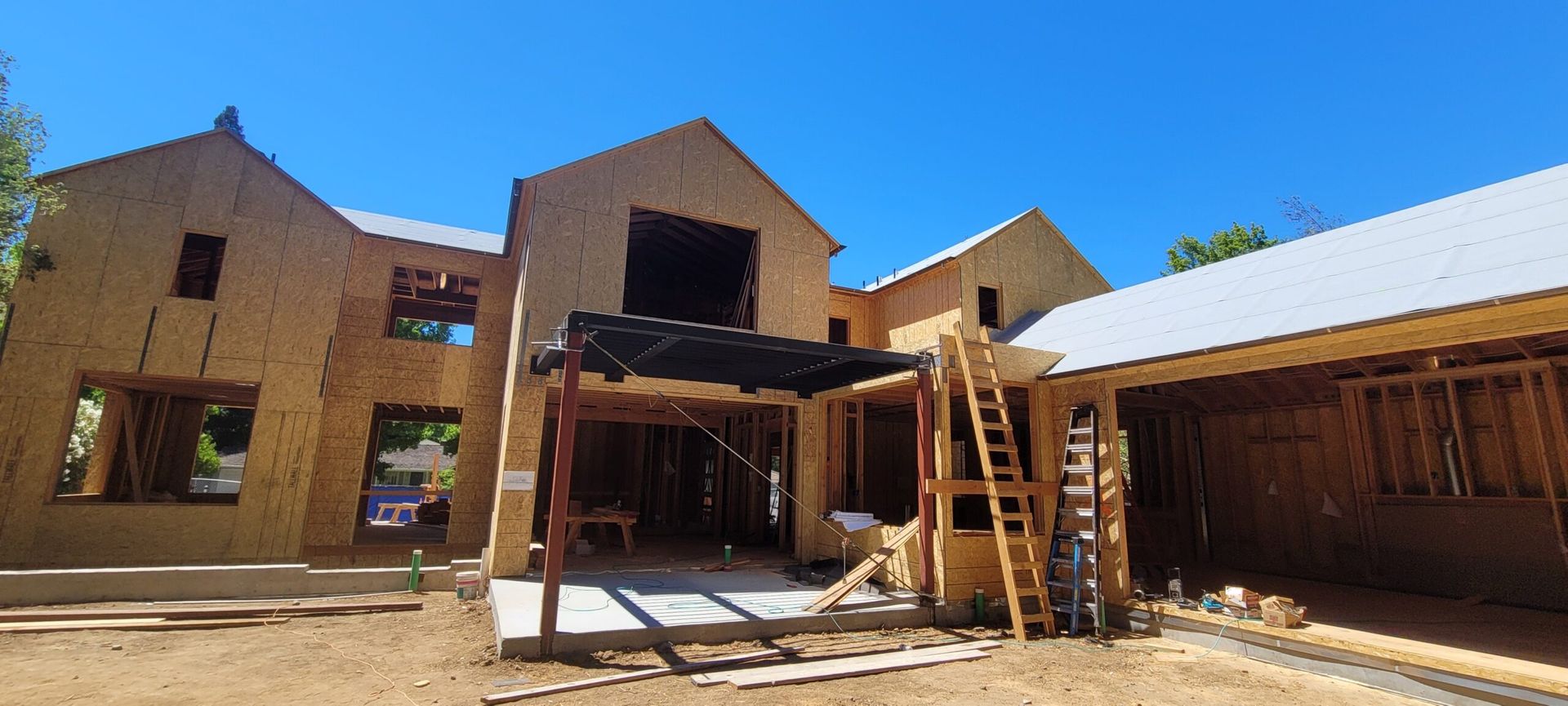 A house under construction with exposed wooden framework against a blue sky.