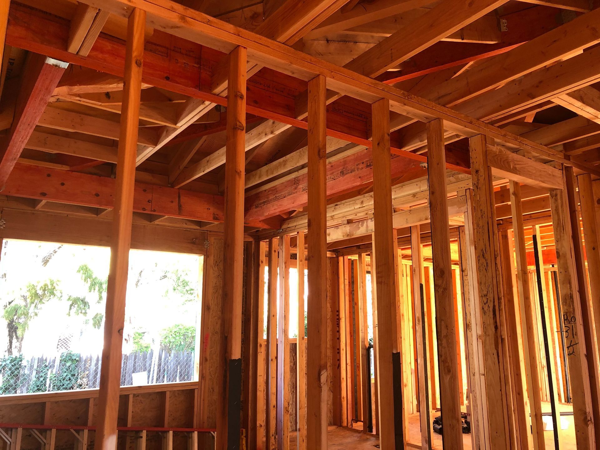 Interior of a house under construction; wooden framing visible, including walls, ceiling, and window frames.