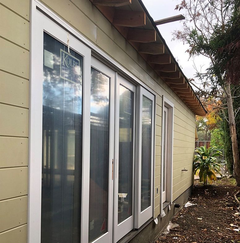 Exterior of a building with white-framed sliding glass doors and a yellow siding.