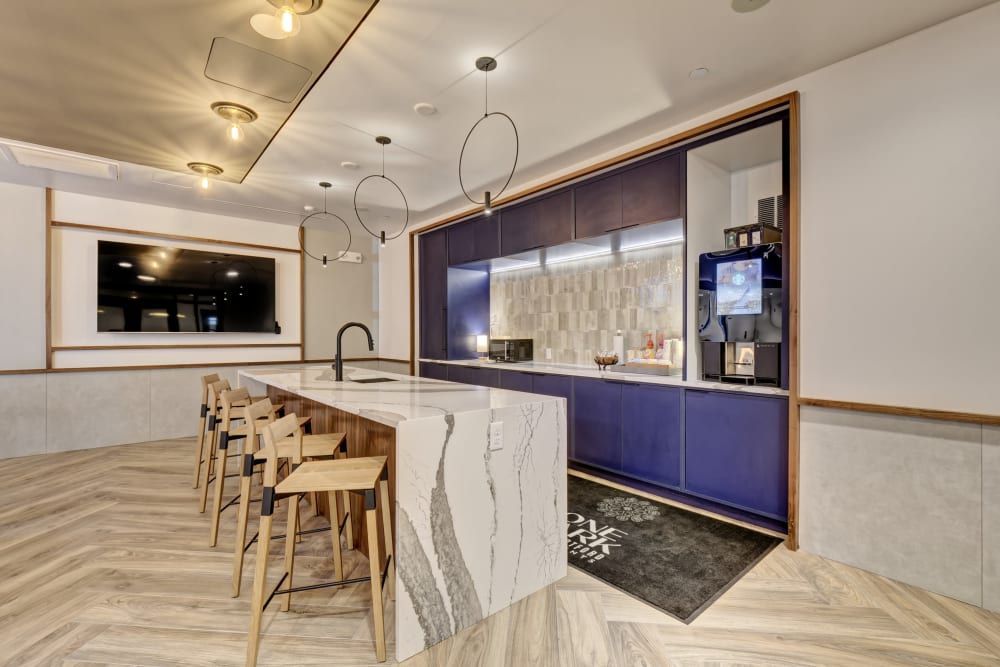 A kitchen with a large island , stools and a tv.