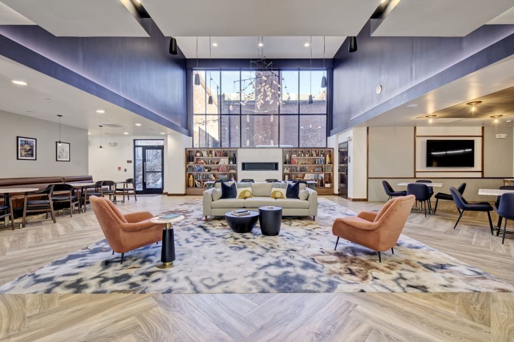 A large living room with a couch , chairs , tables and a fireplace.