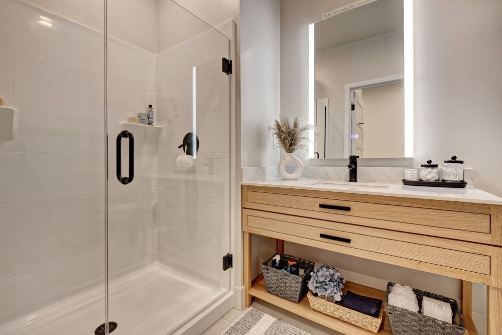 A bathroom with a sink , mirror and walk in shower.