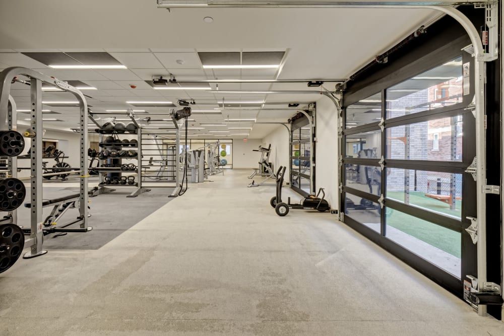 A large gym with a lot of equipment and a garage door.