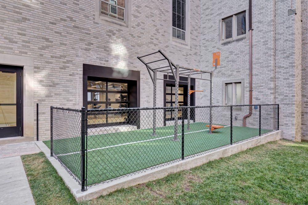 A chain link fence surrounds a playground in front of a brick building.