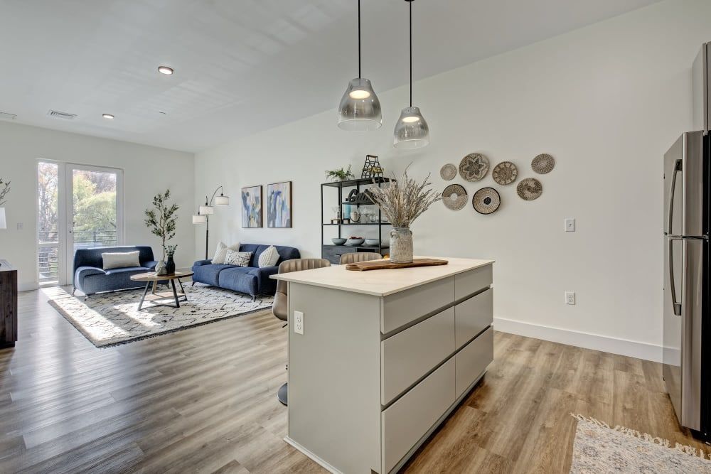 A living room and kitchen in a house with a large island in the middle.
