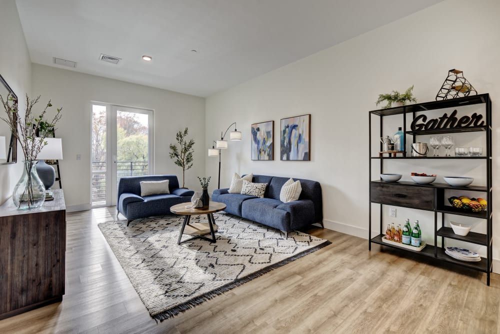 A living room with a blue couch and a white rug.