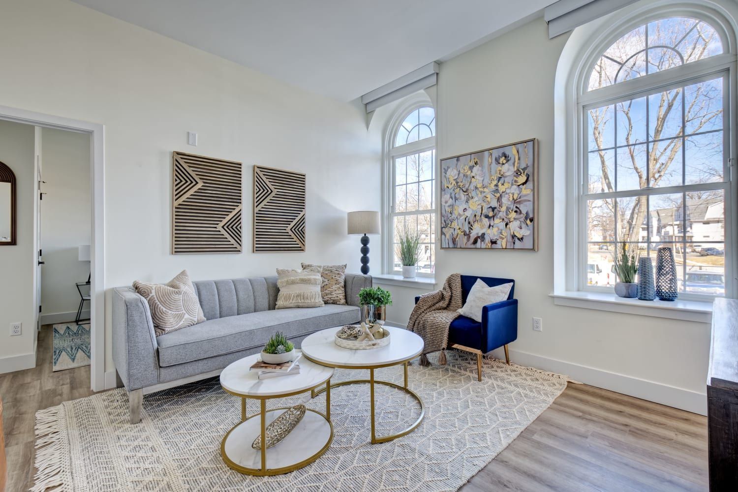 A living room with a couch , chair , two coffee tables and a large window.
