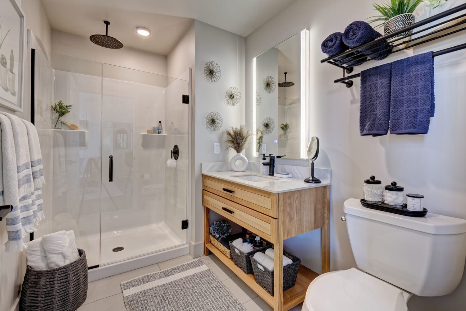 A bathroom with a toilet , sink , shower and mirror.