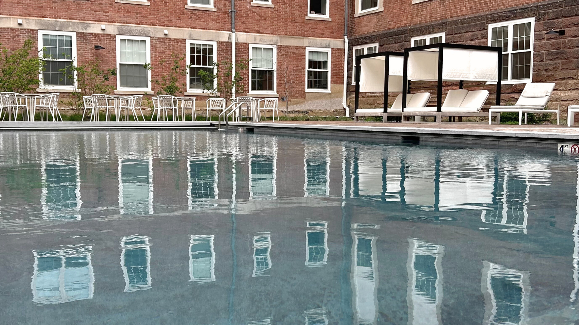 Large heated pool with white cabanas , lounge chairs, and dining table set