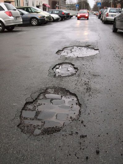 city street with several potholes in asphalt