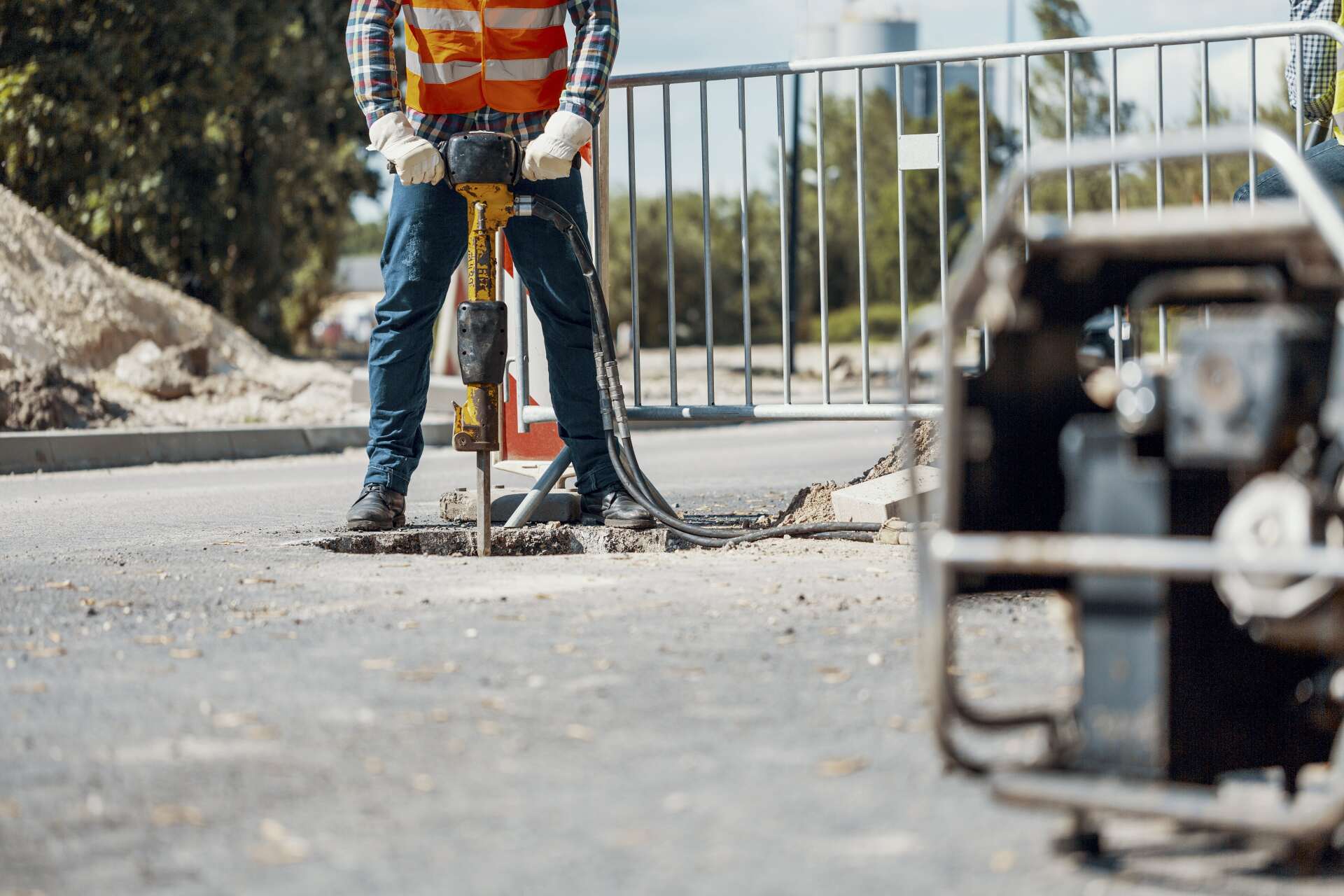 workers in reflective vests using shovels & drill during construction