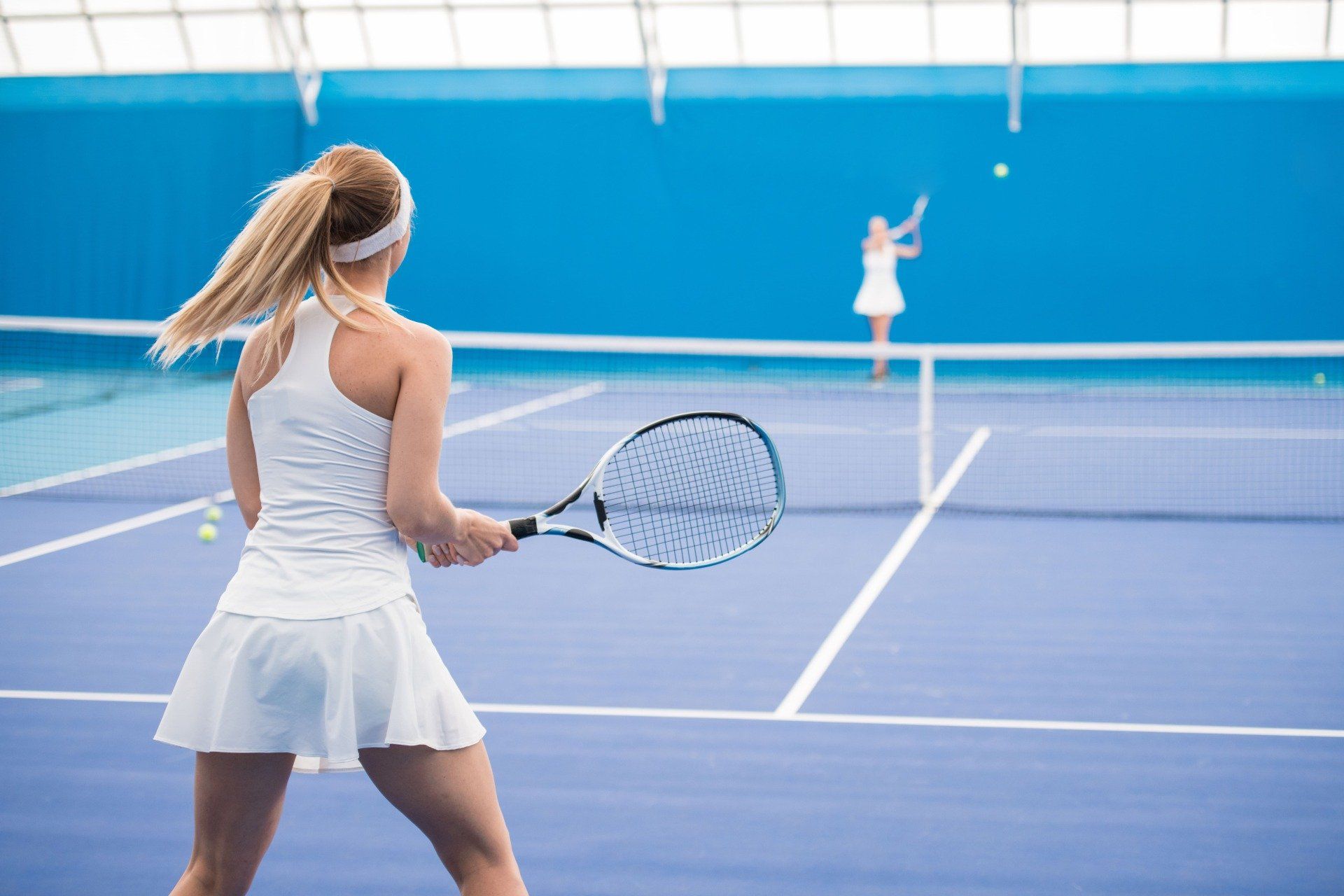 two girls playing on an asphalt tennis court