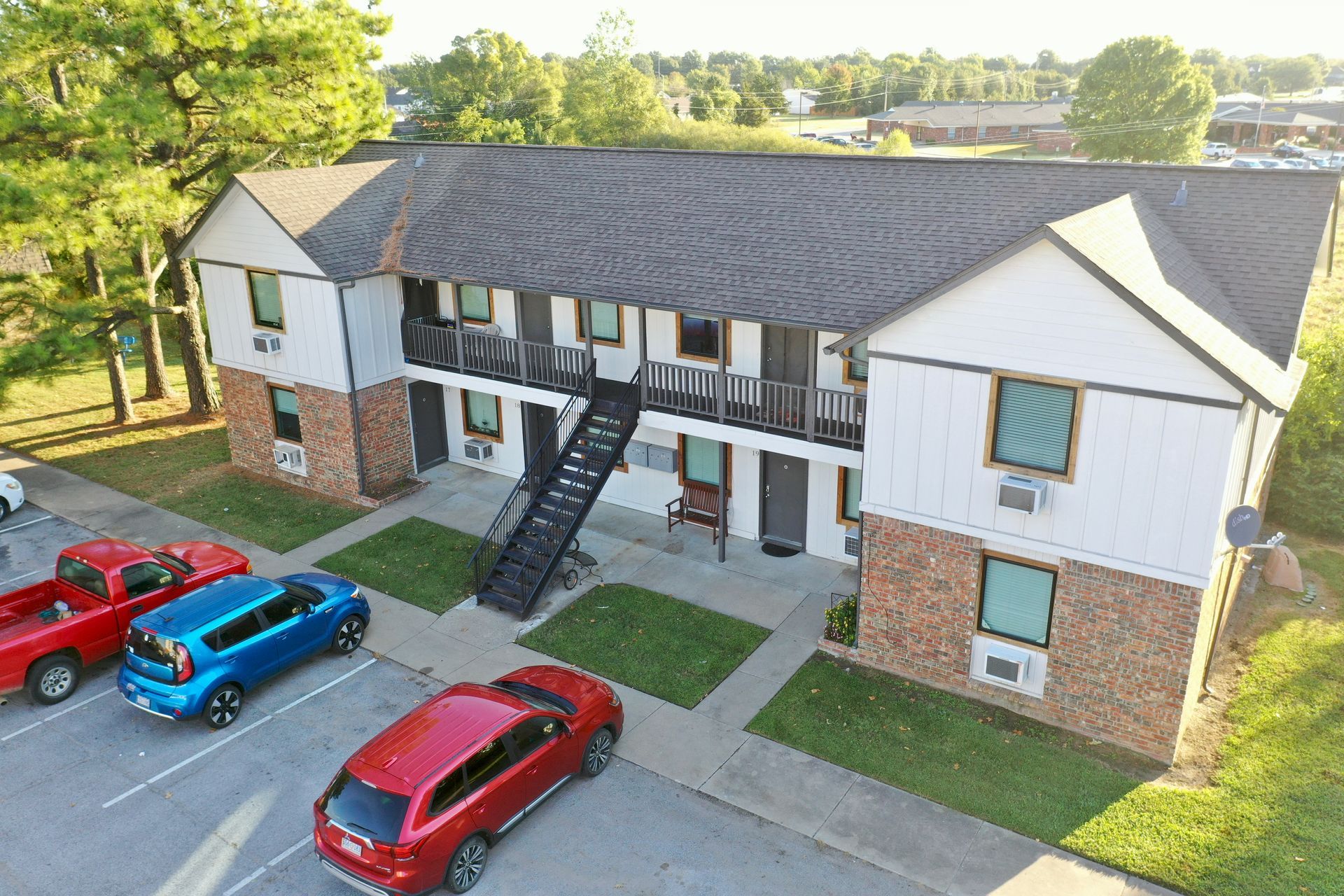 an aerial view of a apartment building with cars parked in front of it .