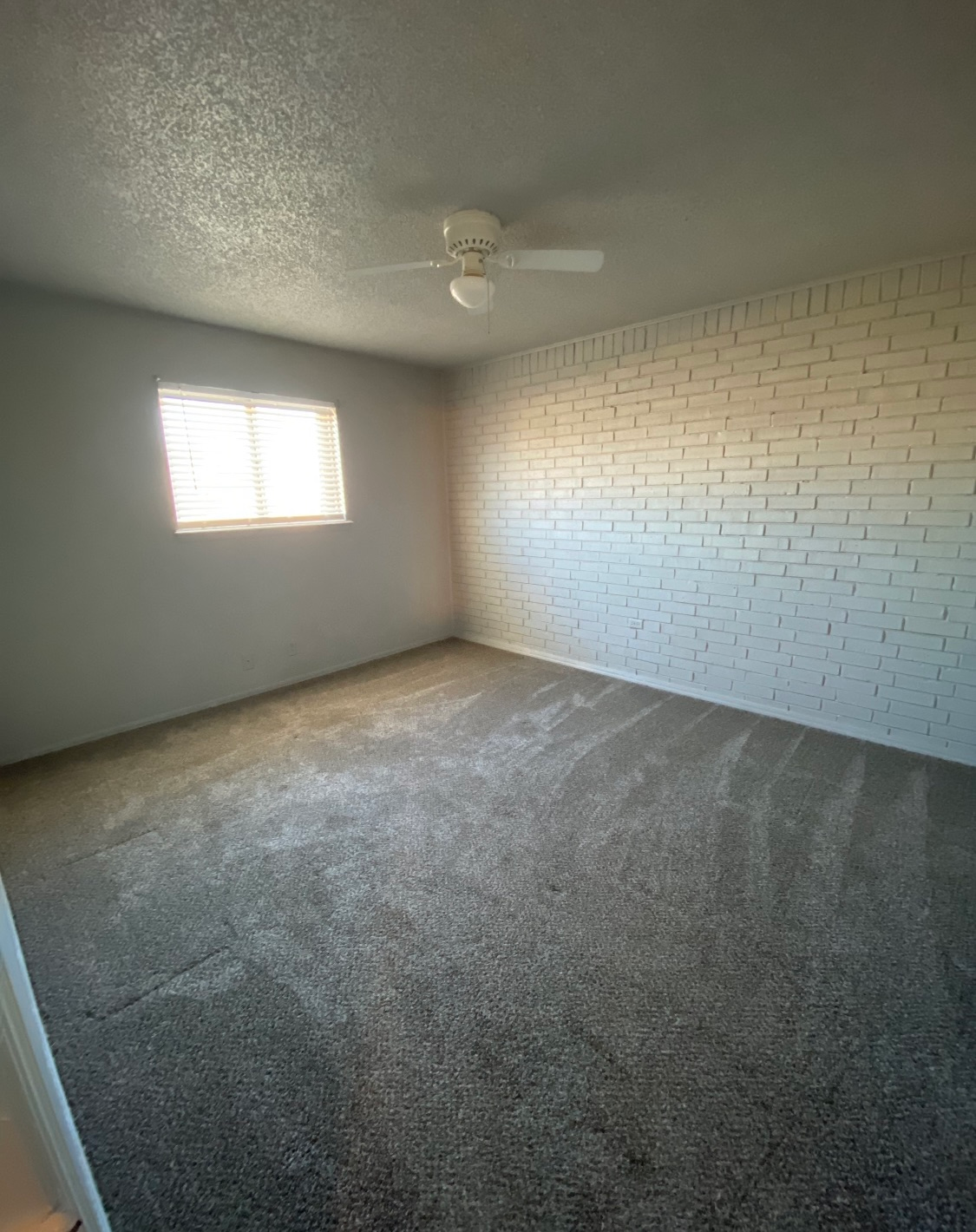 an empty bedroom with a ceiling fan and a window .