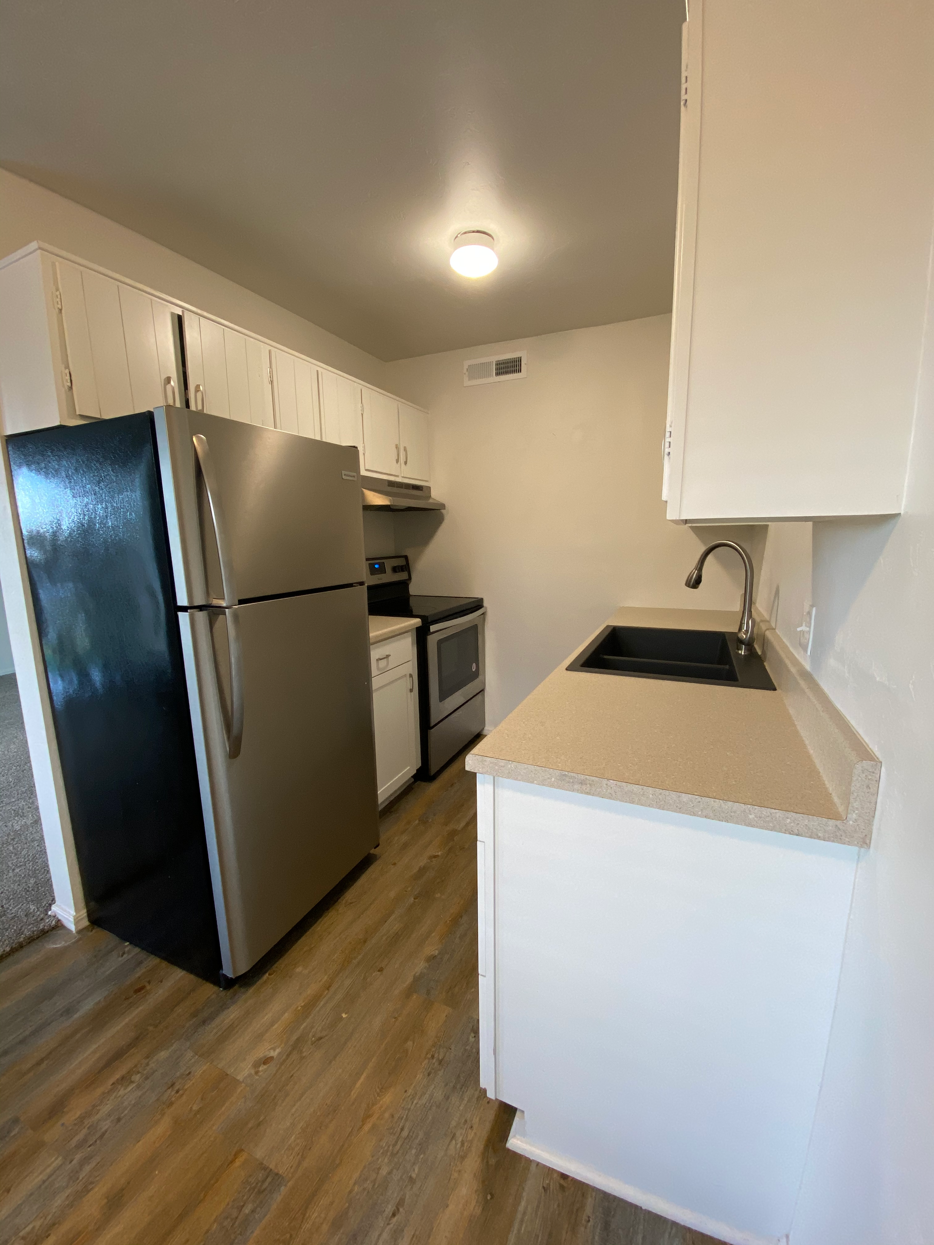 a kitchen with a refrigerator , stove , sink and cabinets .