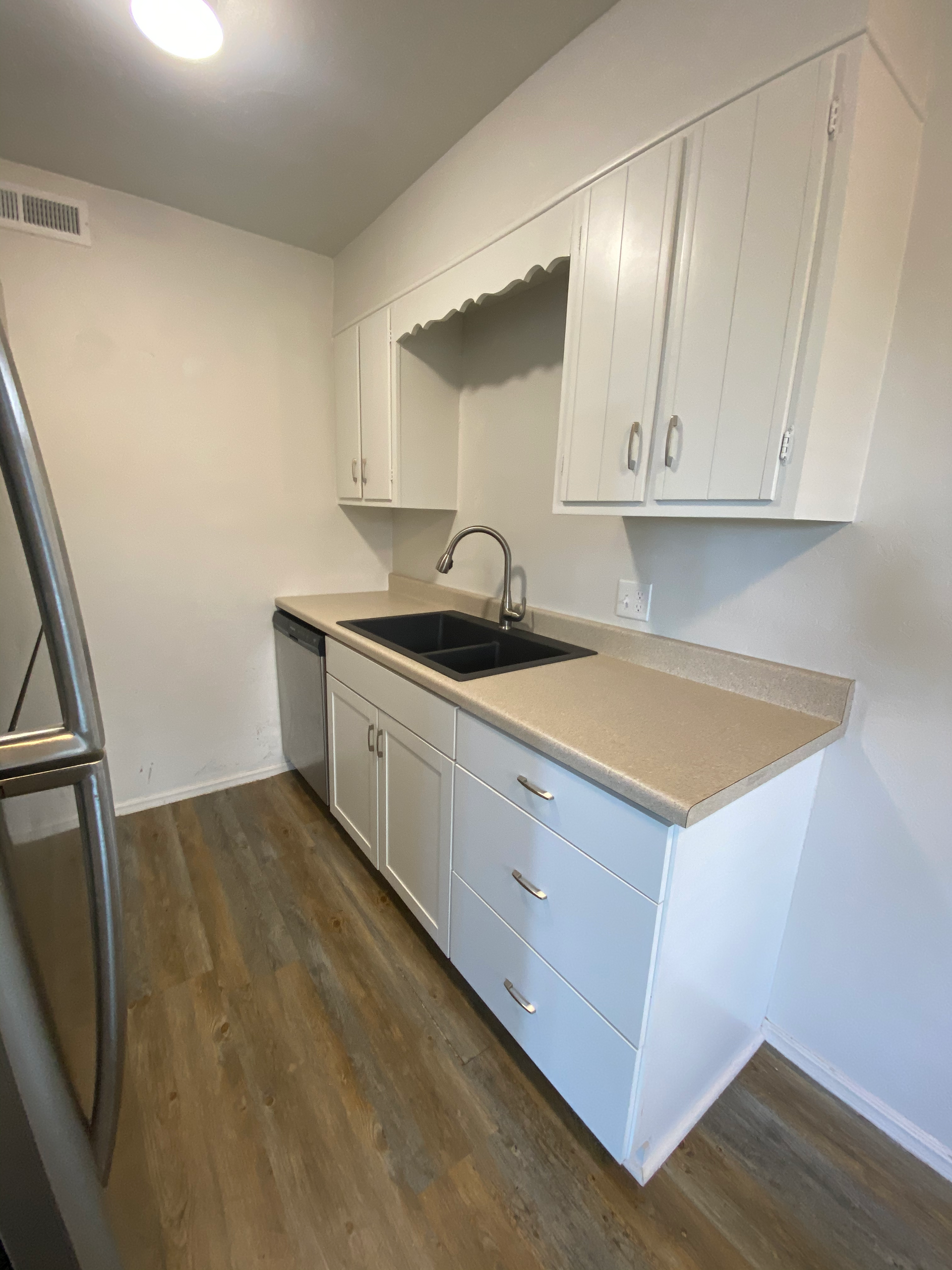 a kitchen with white cabinets , a sink , and a refrigerator .