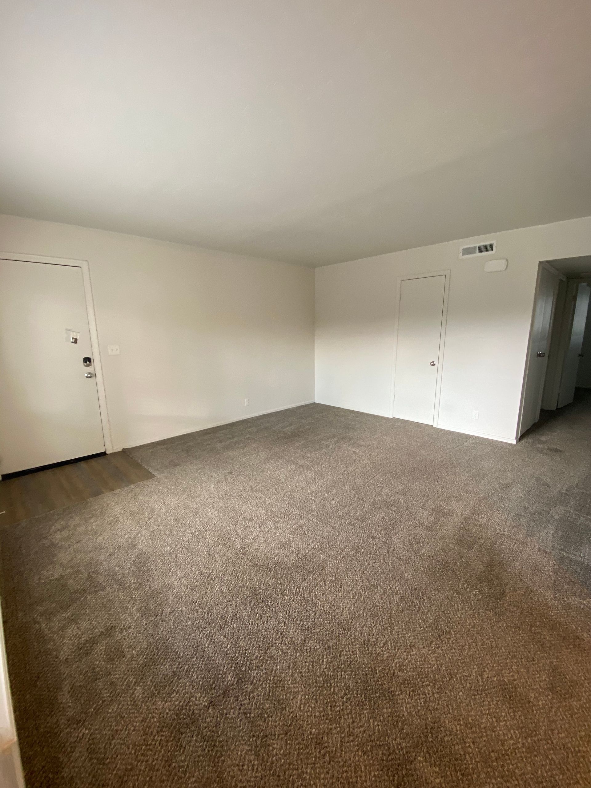 an empty living room with a carpeted floor and white walls .