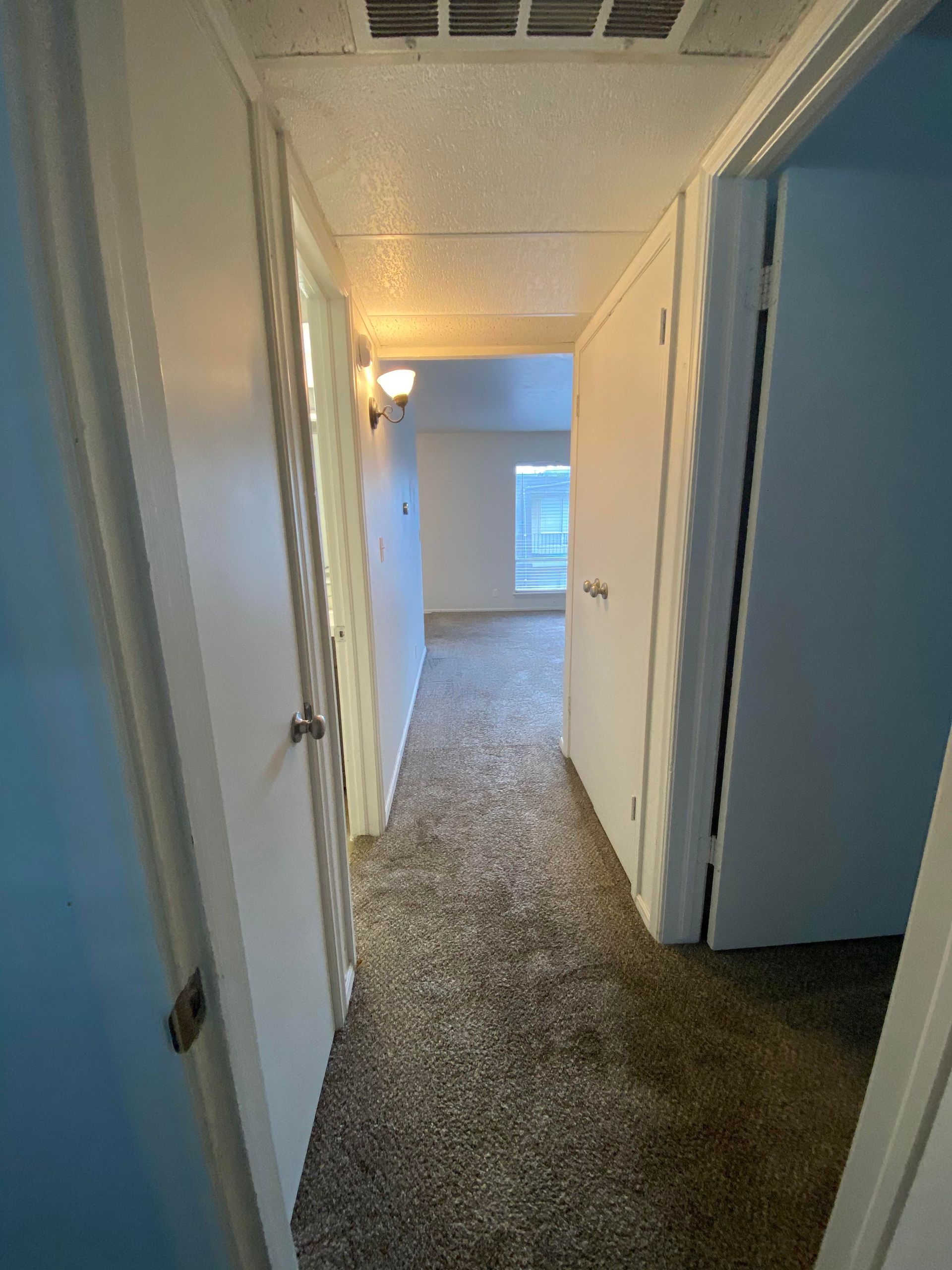 a hallway in a house with a carpeted floor and a window .