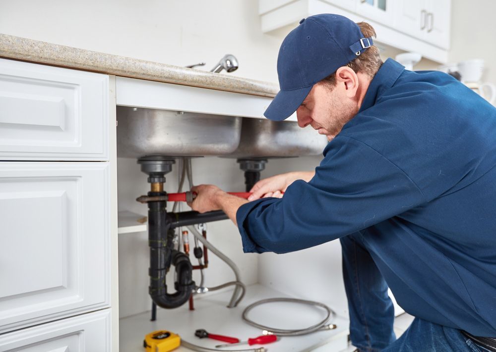 A Plumber is Fixing a Sink in a Kitchen — Absolute Plumbing Australia in Darwin, NT