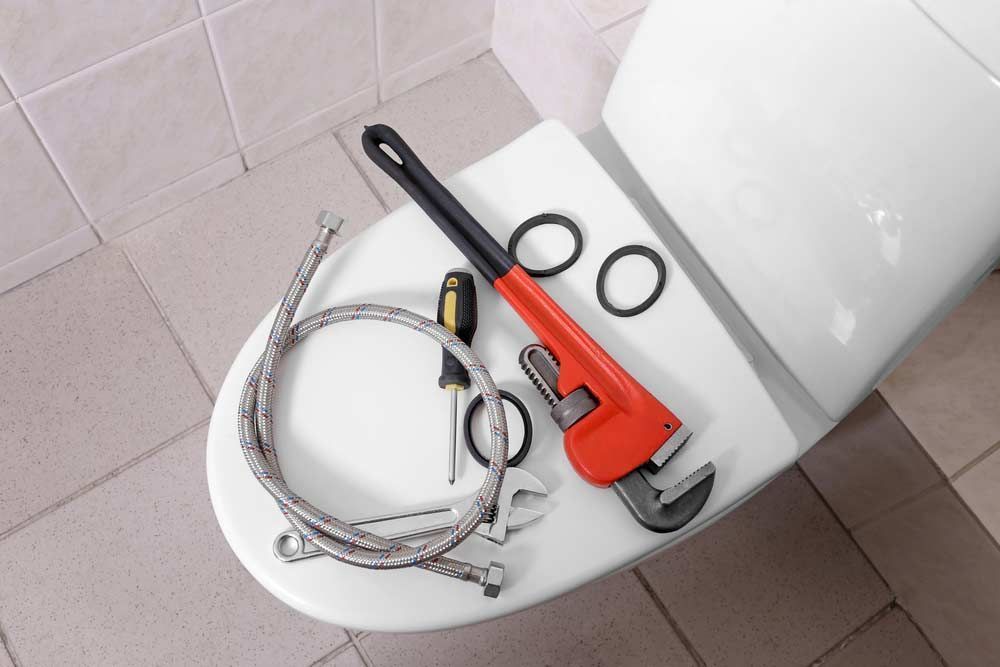 A Toilet With a Wrench and Hose on It — Absolute Plumbing Australia in Darwin, NT