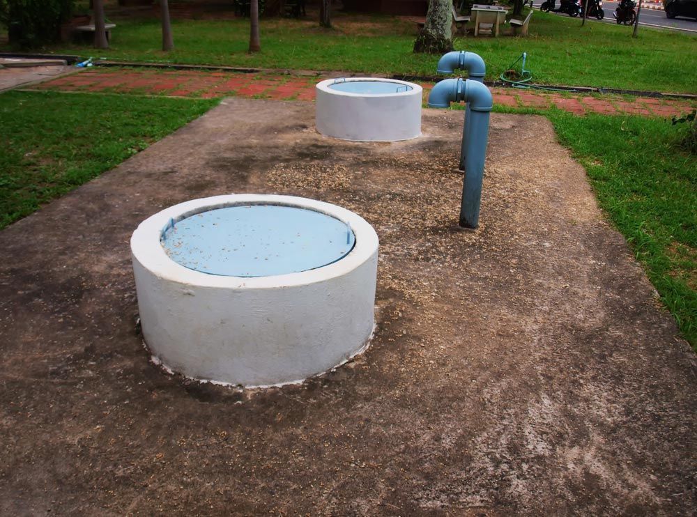 A Concrete Circle With Blue Lid in a Park — Absolute Plumbing Australia in Darwin, NT