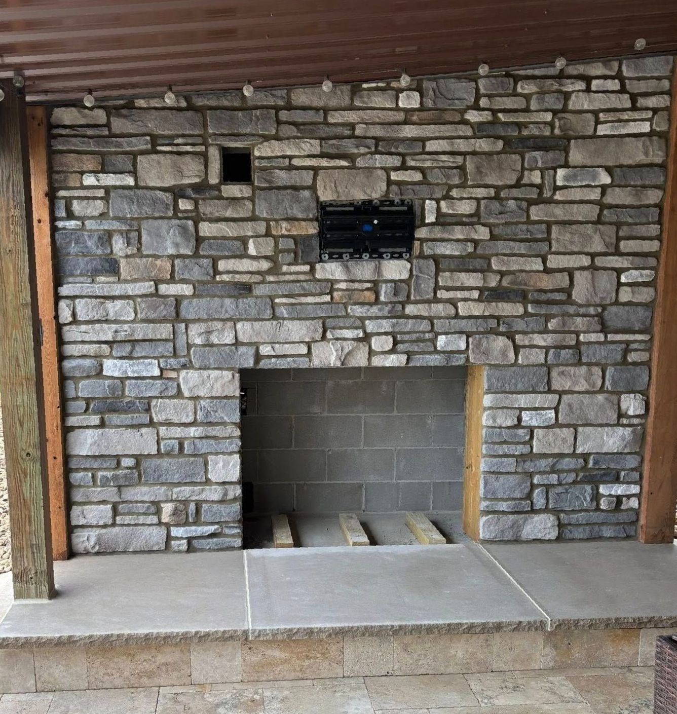 A brick fireplace is being built on a patio next to a pool.