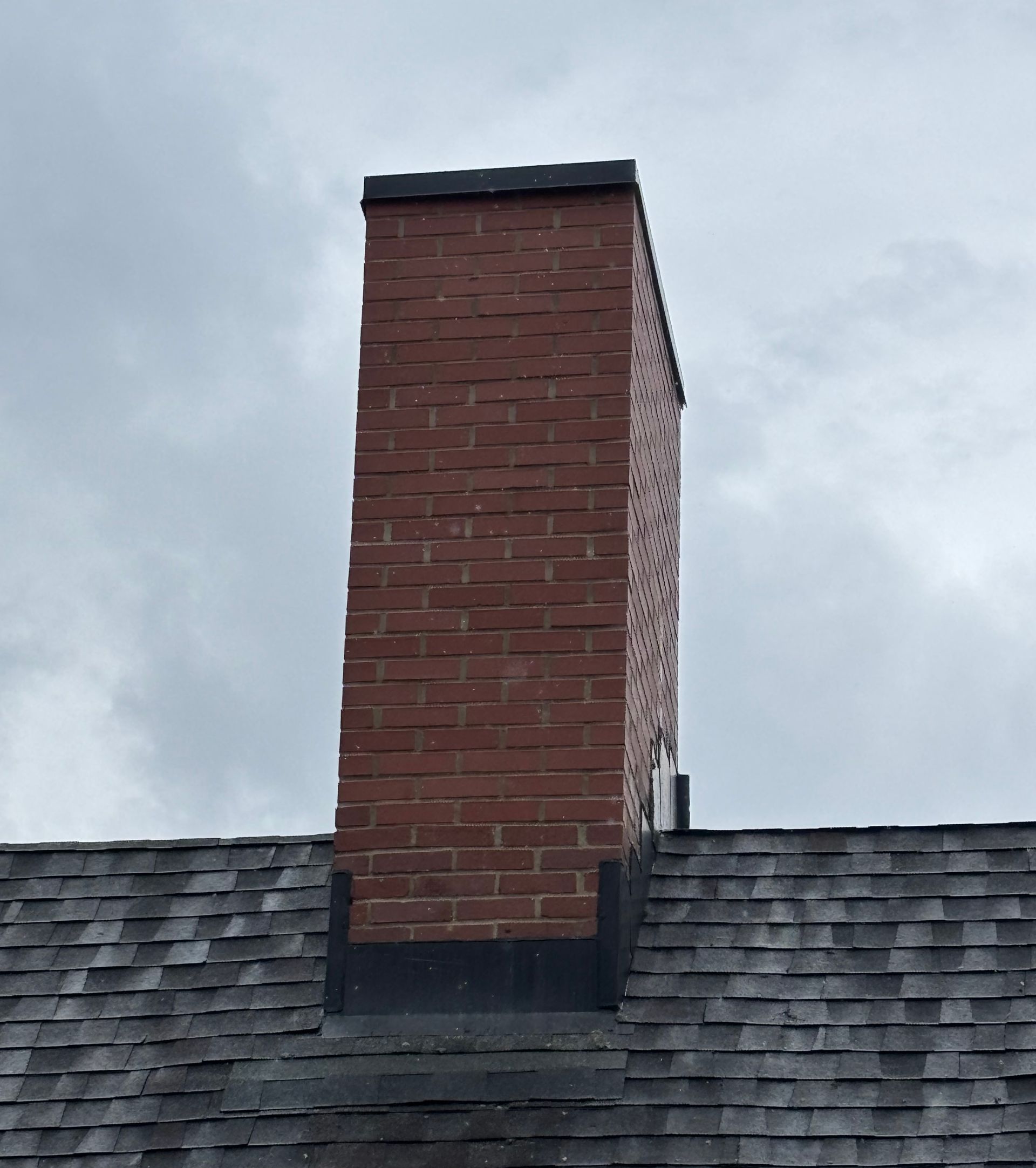 A close up of a brick chimney on a roof.
