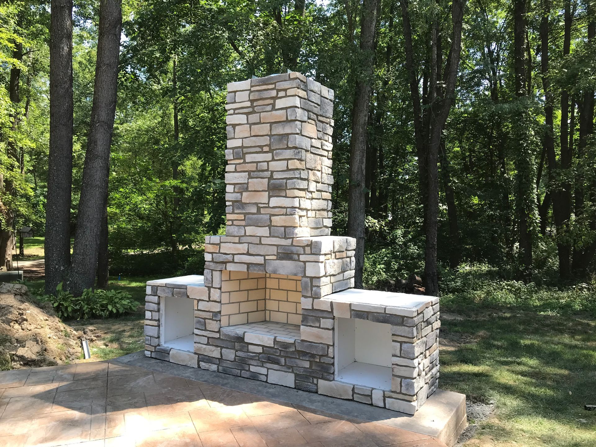 A stone fireplace is under a wooden gazebo.