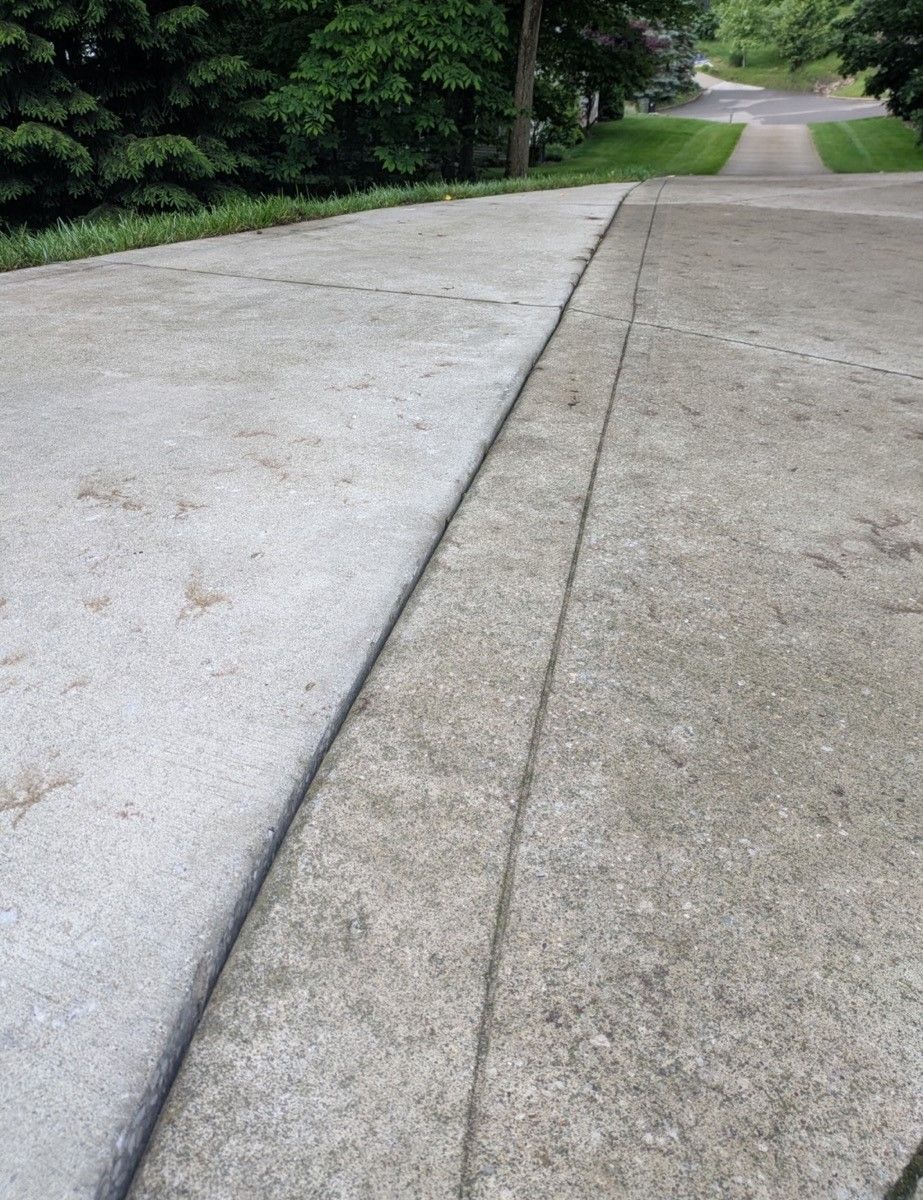A concrete driveway with a few trees on the side of it.