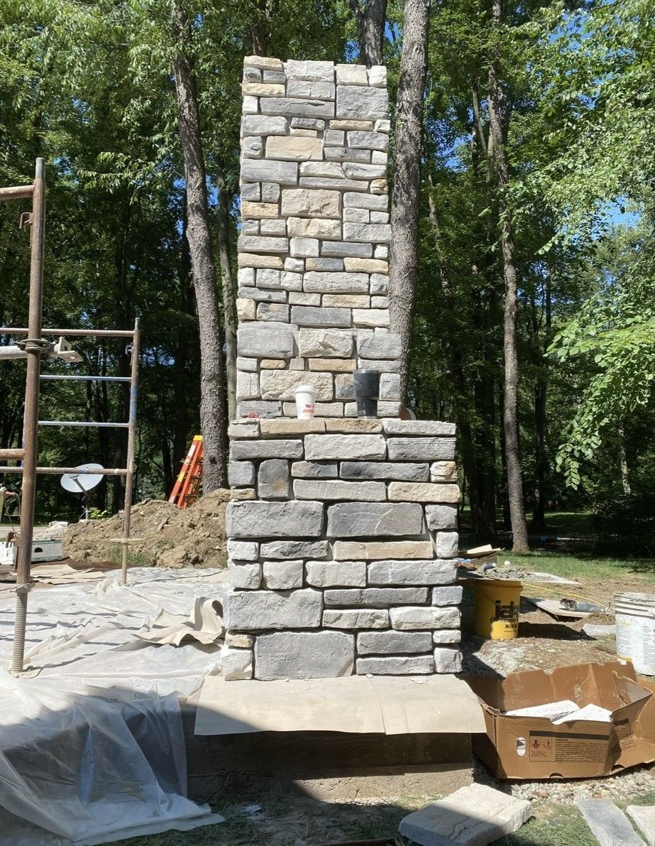 A stone chimney is being built in the middle of a forest