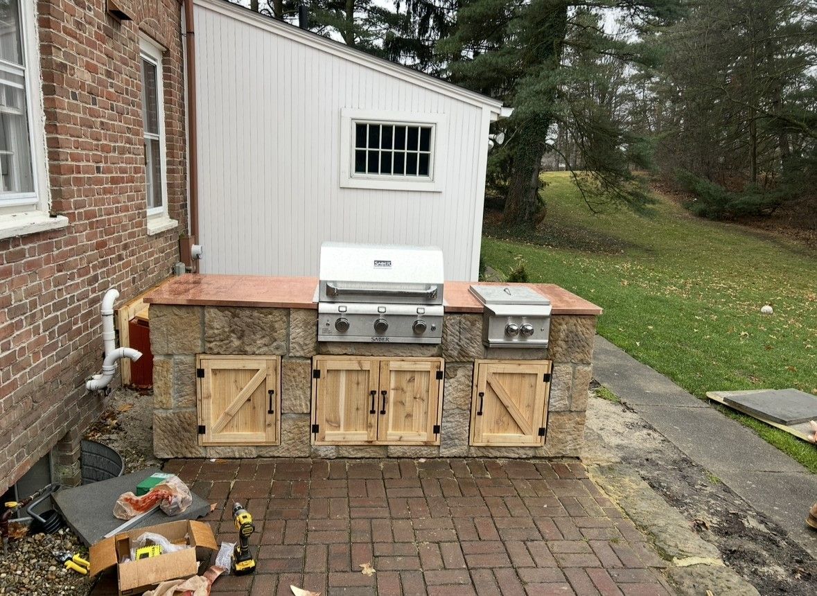 A grill is sitting on a brick patio next to a brick building.