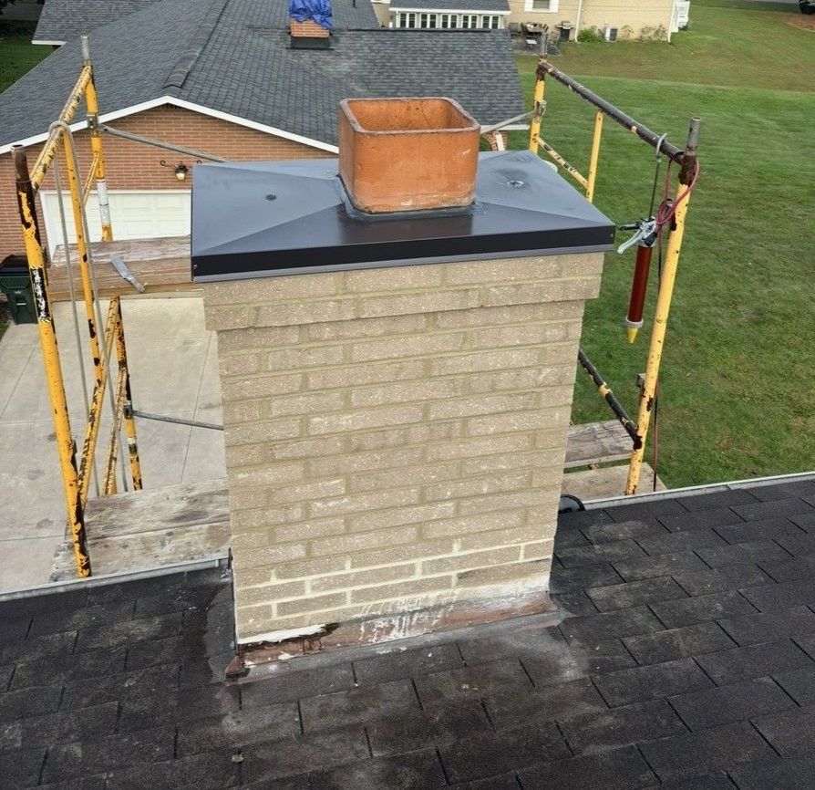 A brick chimney is sitting on top of a roof.