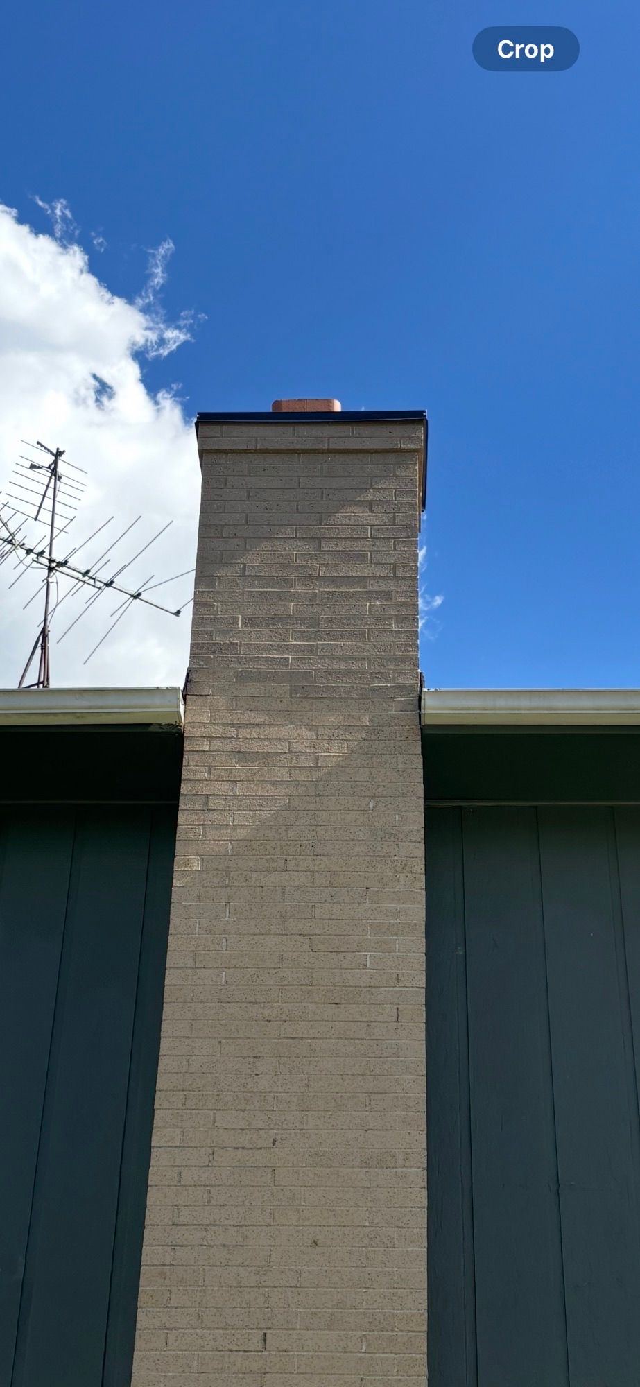 A brick chimney on top of a building with a blue sky in the background.
