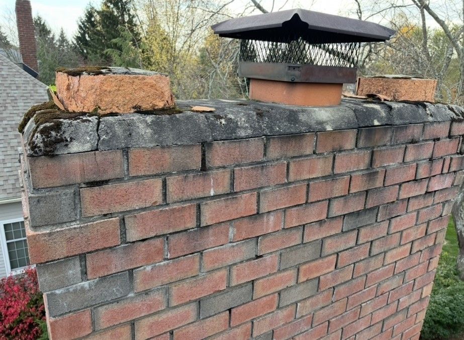 A brick chimney with a metal cap on top of it.
