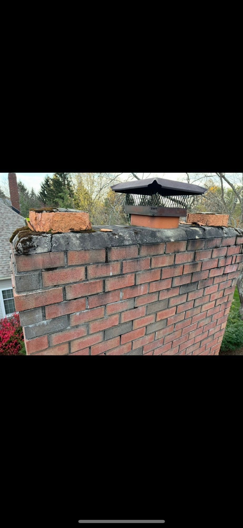 A man is working on a brick chimney on a roof.