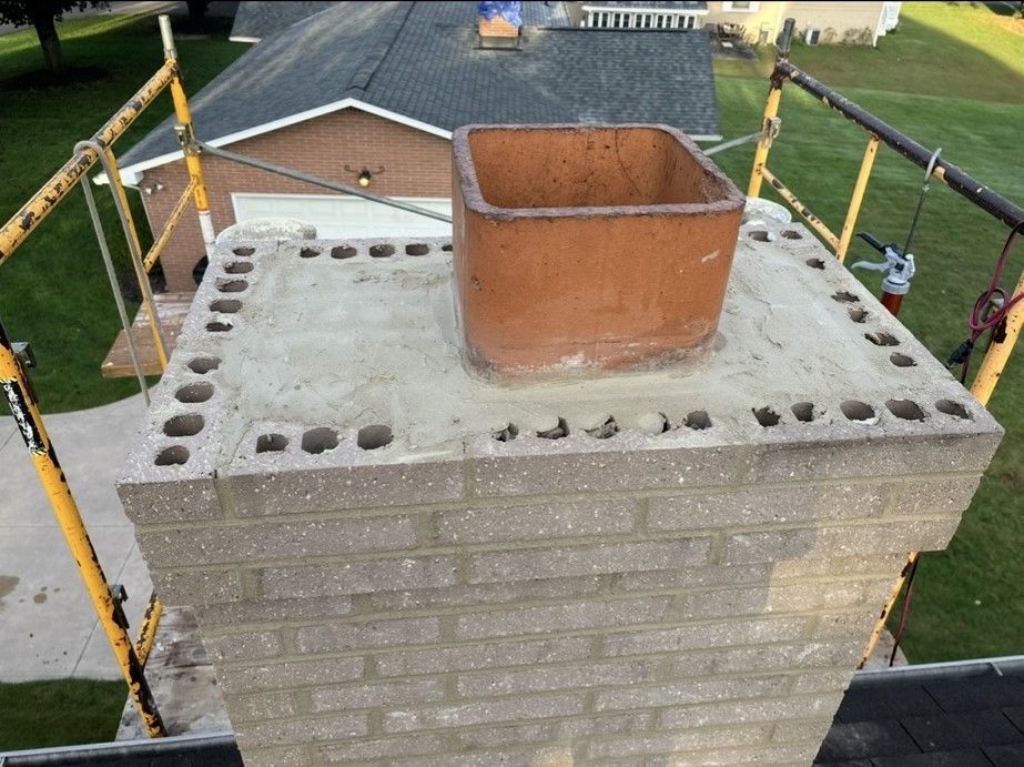 A brick chimney sitting on top of a scaffolding in front of a house