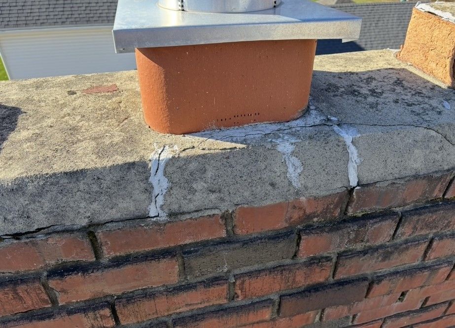 A brick chimney is sitting on top of a brick wall.
