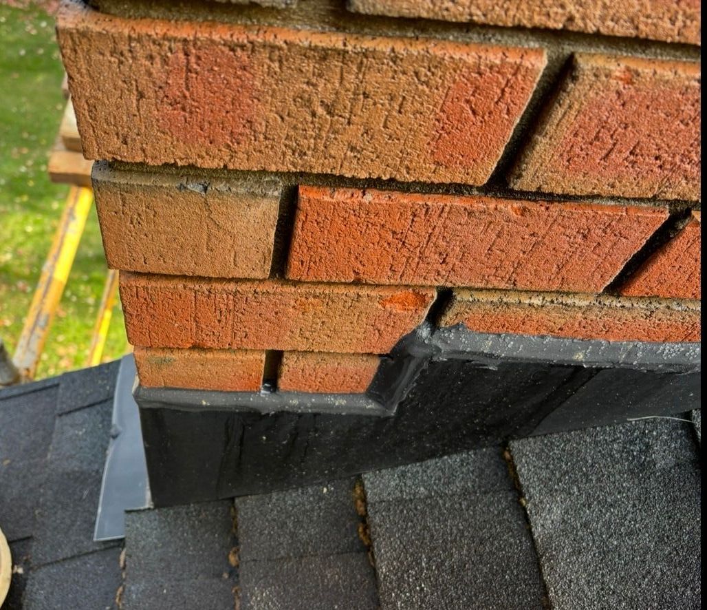 A man wearing a hard hat and safety vest is working on a chimney.