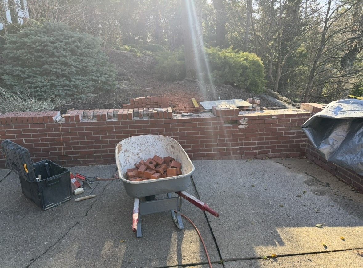 A wheelbarrow filled with bricks is sitting on a patio next to a brick wall.