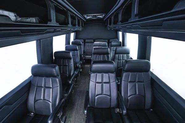 The inside of a bus with lots of black leather seats.