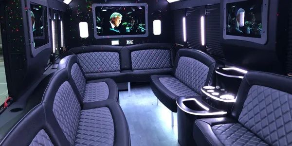 The inside of a limousine with purple seats and a television.