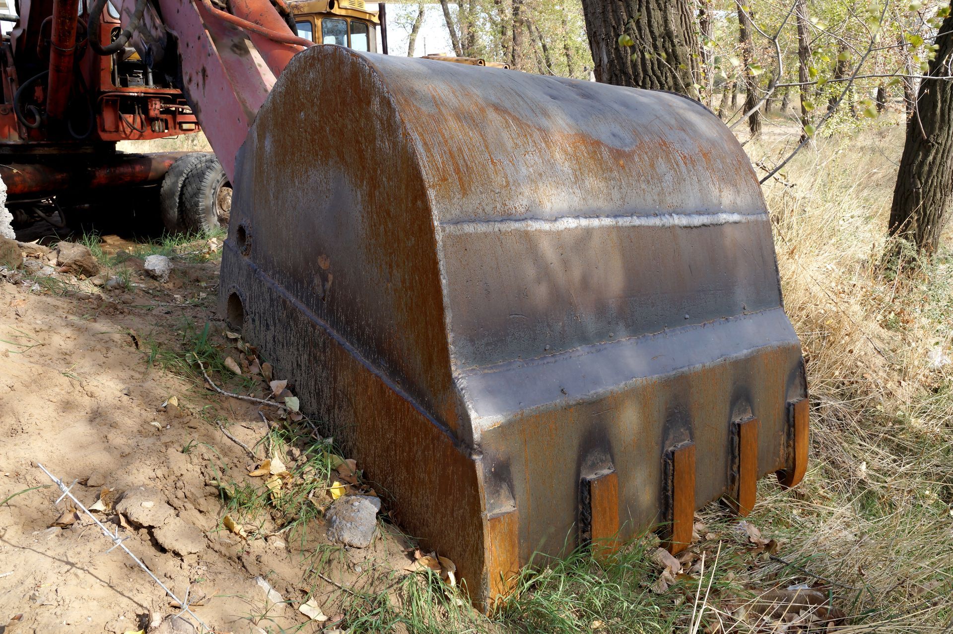 a rusty excavator bucket is sitting in the grass