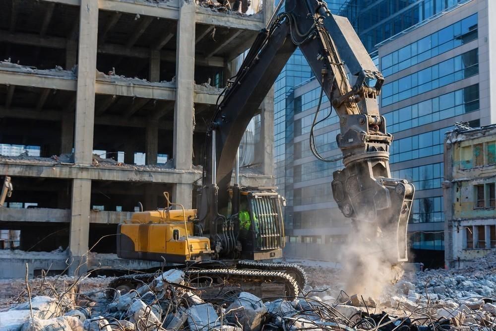 a large excavator is demolishing a building in a city .