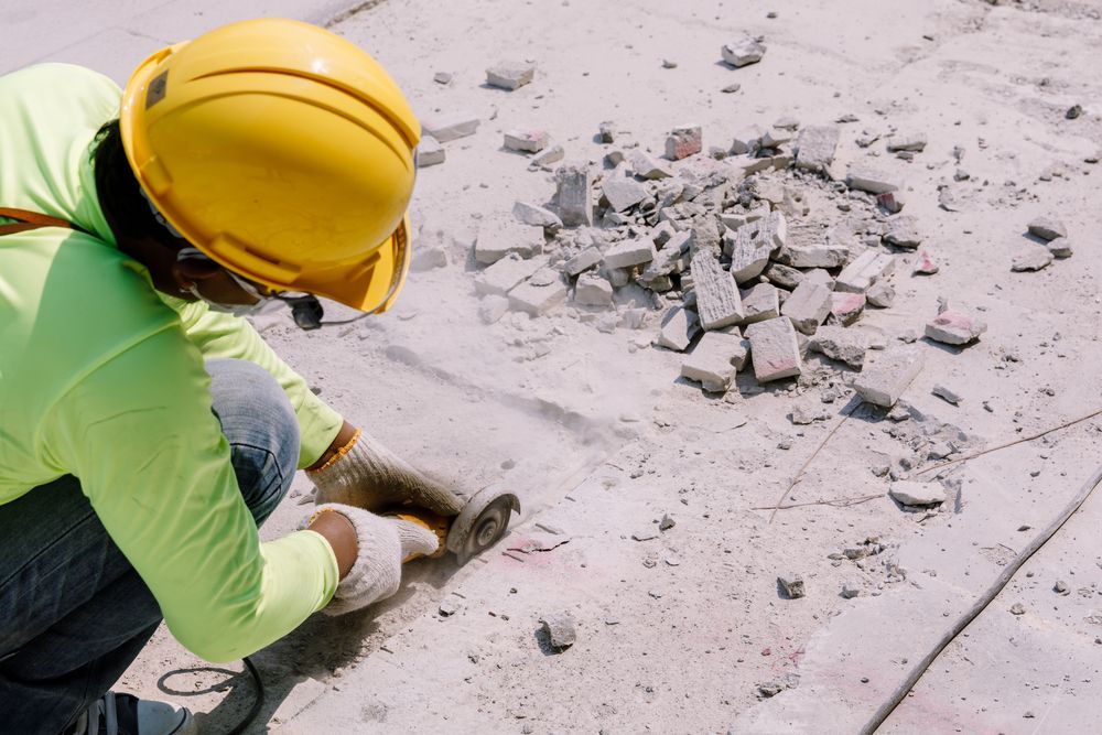 Construction Worker in Yellow Helmet Cuts Concrete — Ecowave Solutions In Gosford, NSW