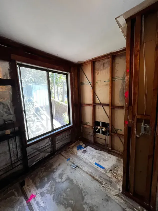 Bathroom Under Renovation With Exposed Studs, Window, and Debris on the Floor — Ecowave Solutions In Gosford, NSW