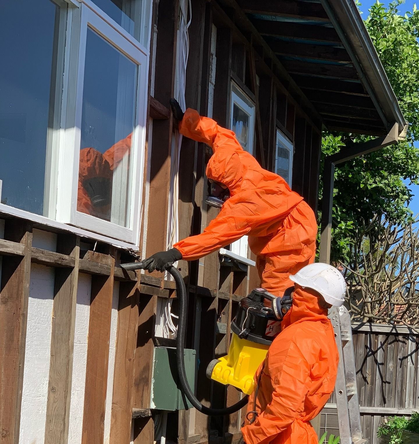 Two People in Orange Protective Suits Working on a House Exterior — Ecowave Solutions In Gosford, NSW