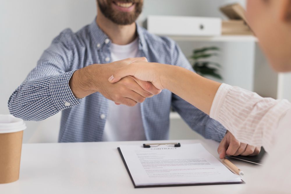 A man and a woman are shaking hands during a job interview.