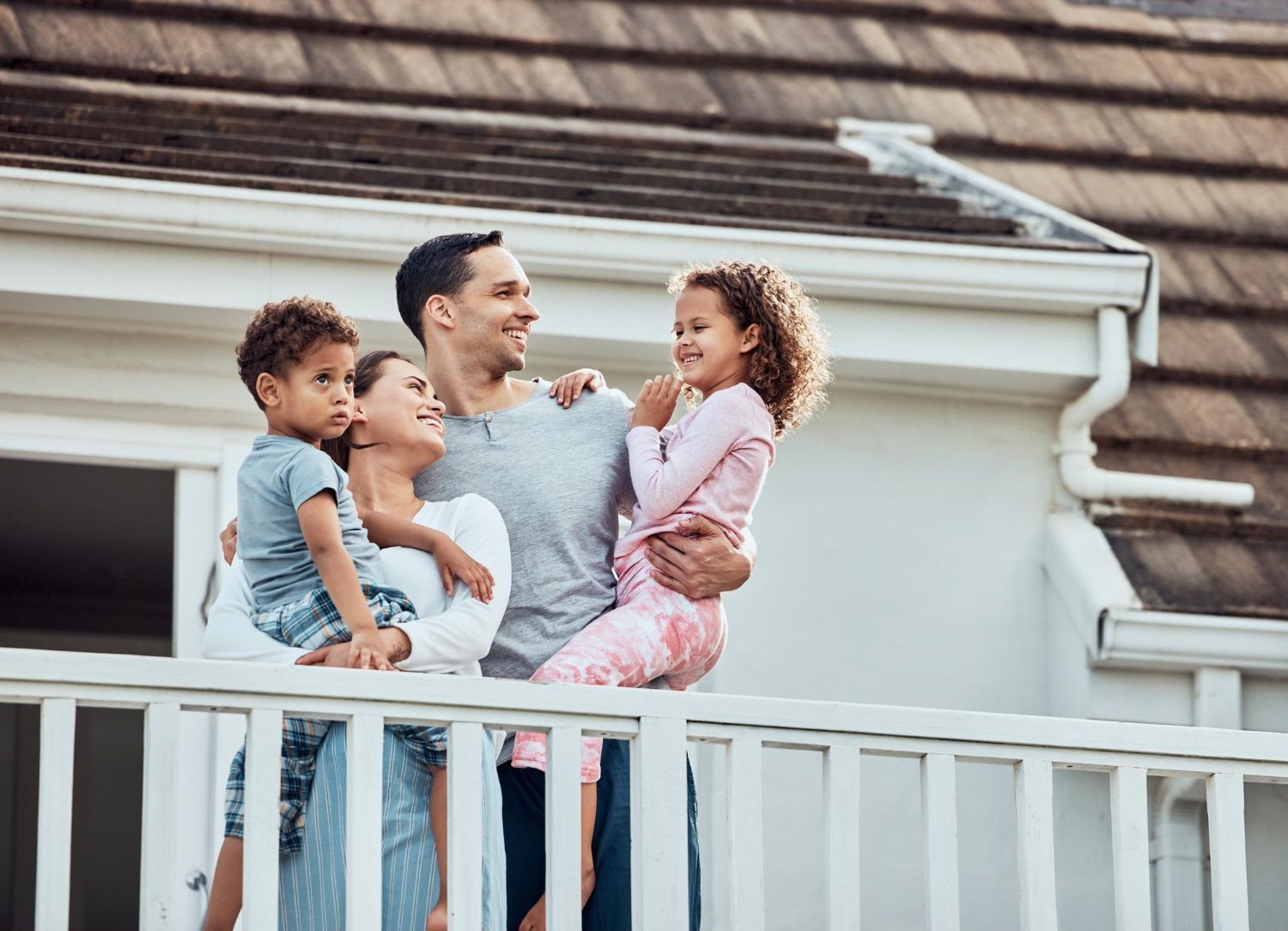 A family is standing on a balcony of their house.