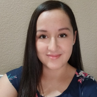 A woman with long hair is wearing a blue shirt and smiling for the camera.