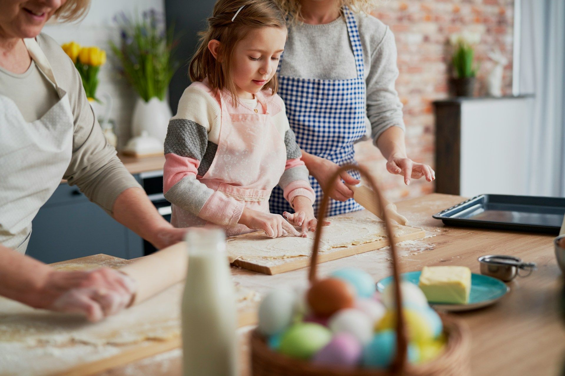 A woman and two children are preparing food in a kitchen.